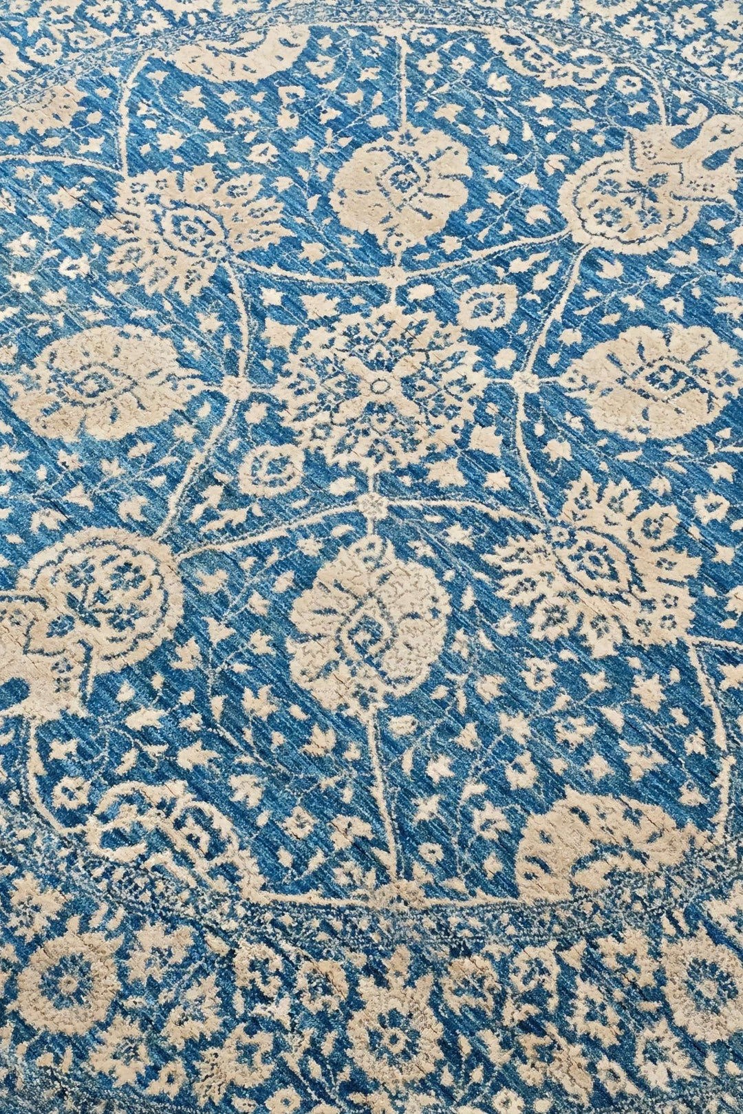 Radial floral detail in slate blue and cream on round Ghazni rug