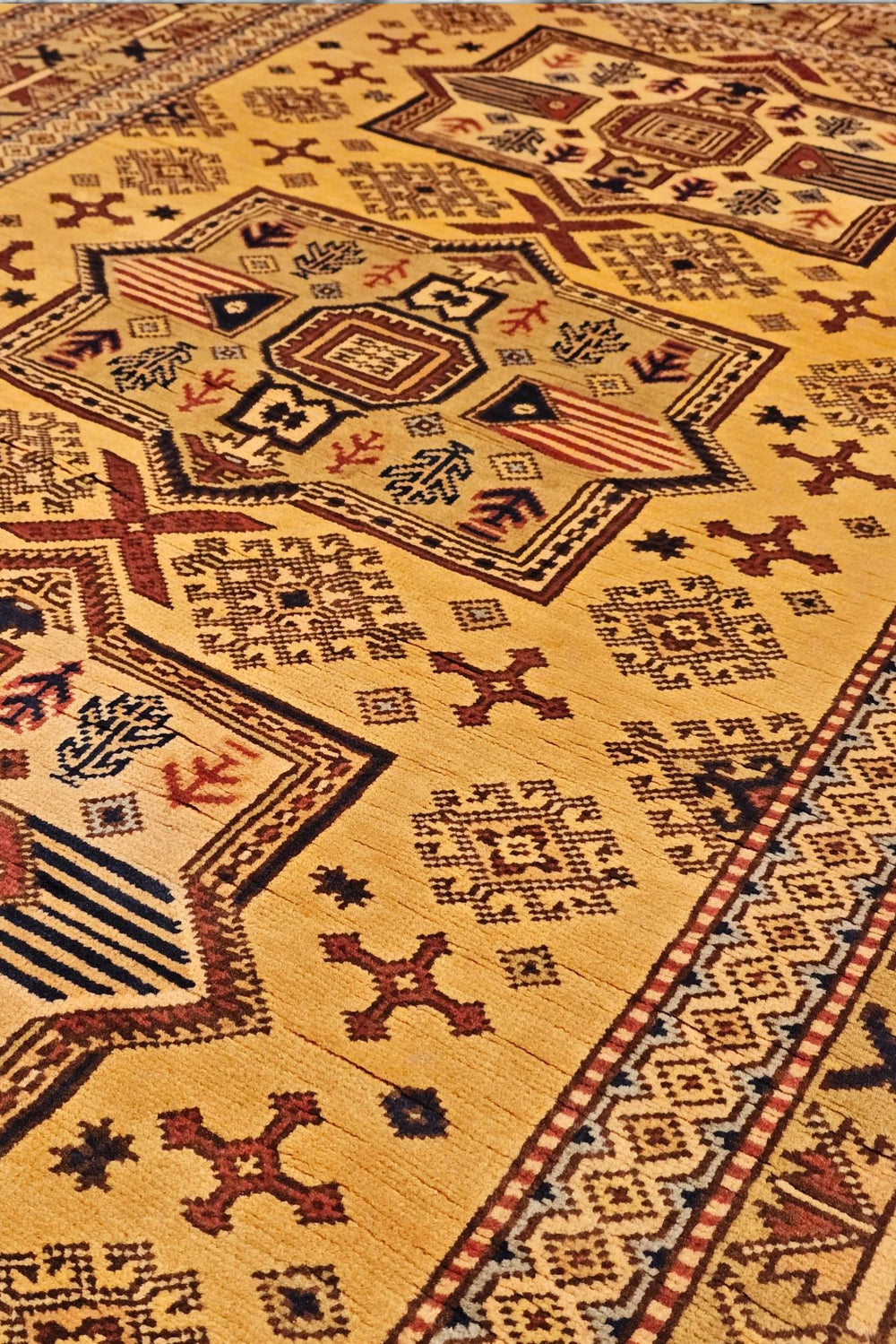 Tribal star detail in gold on Kazak rug