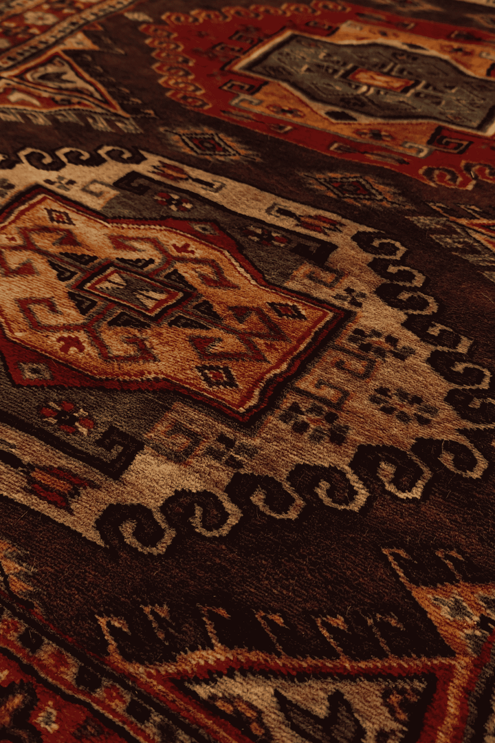 Scrolled medallion detail in espresso and madder red on Kazak runner