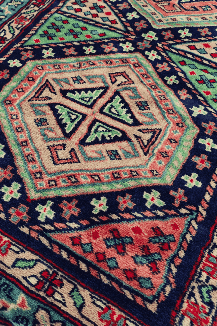 Hexagonal medallion detail in navy and rose on Kazak runner