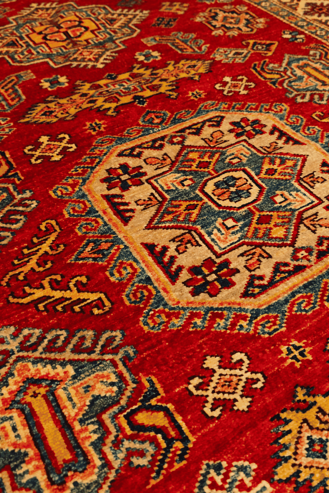 Border detail of red gold gül Kazak rug
