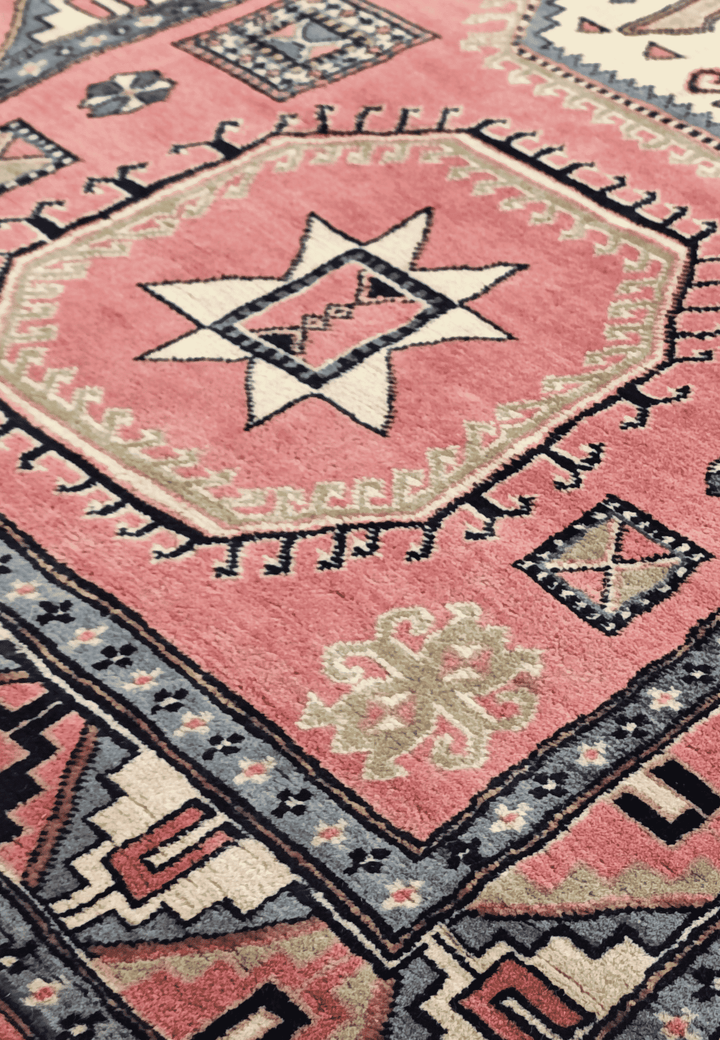 Star and cross medallion detail in rose and ivory on Kazak rug