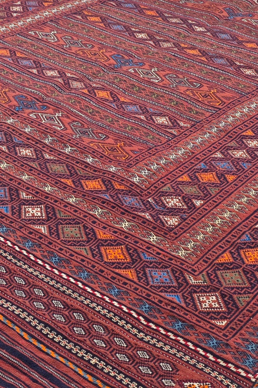 Banded detail in rose red and orange on Afghan kilim