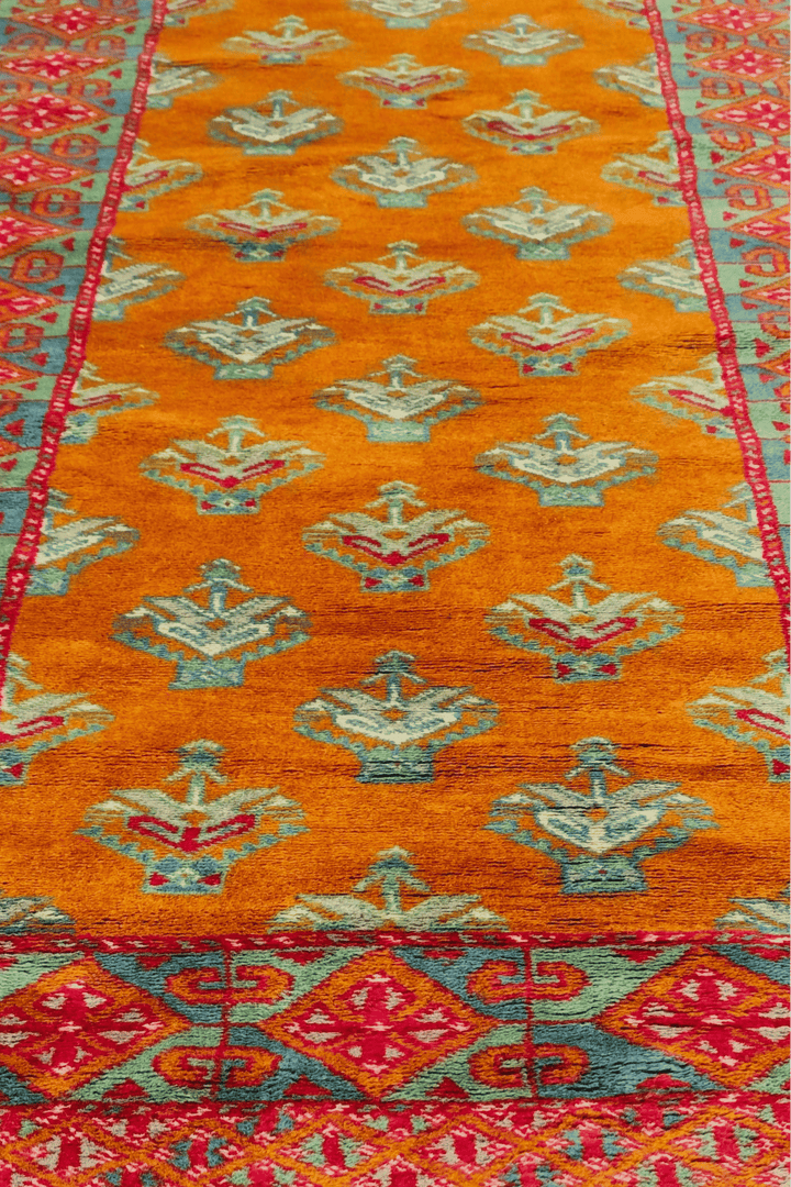 Hand-knotted saffron runner with teal flowering shrub repeat