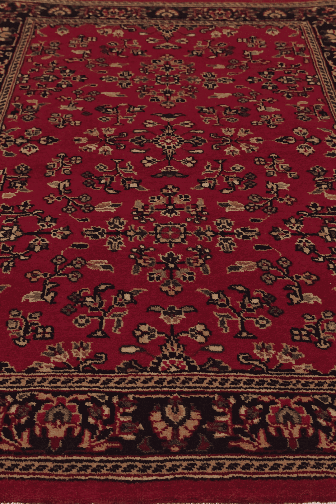 Corner of madder red Sarouk hand-knotted Indian rug