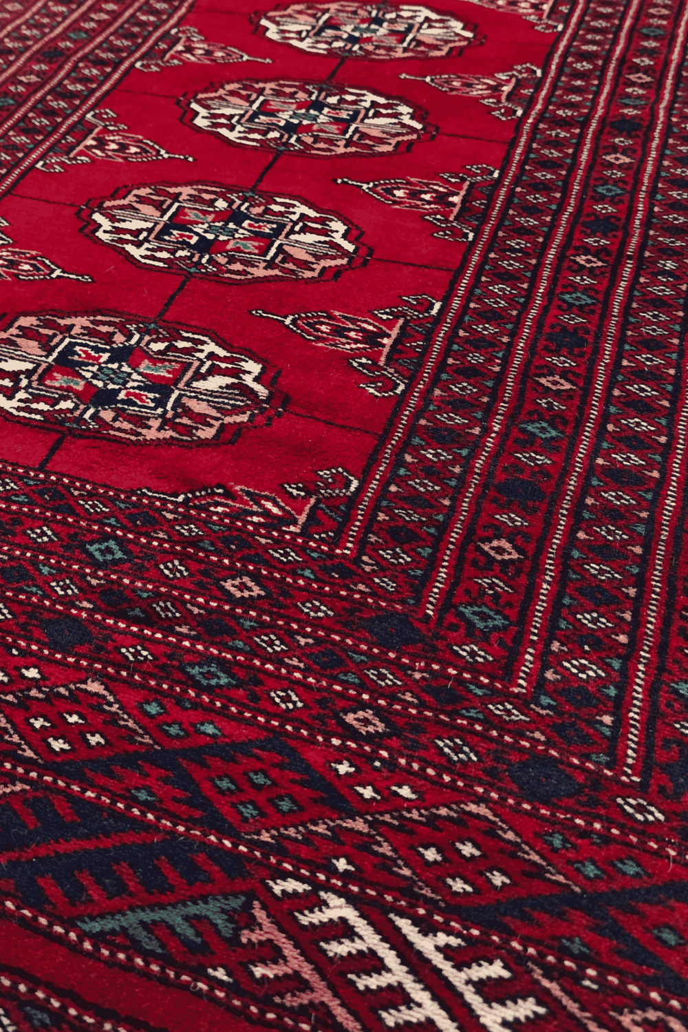 Turkmen gül motifs in ivory, rose and navy on crimson Bokhara wool rug