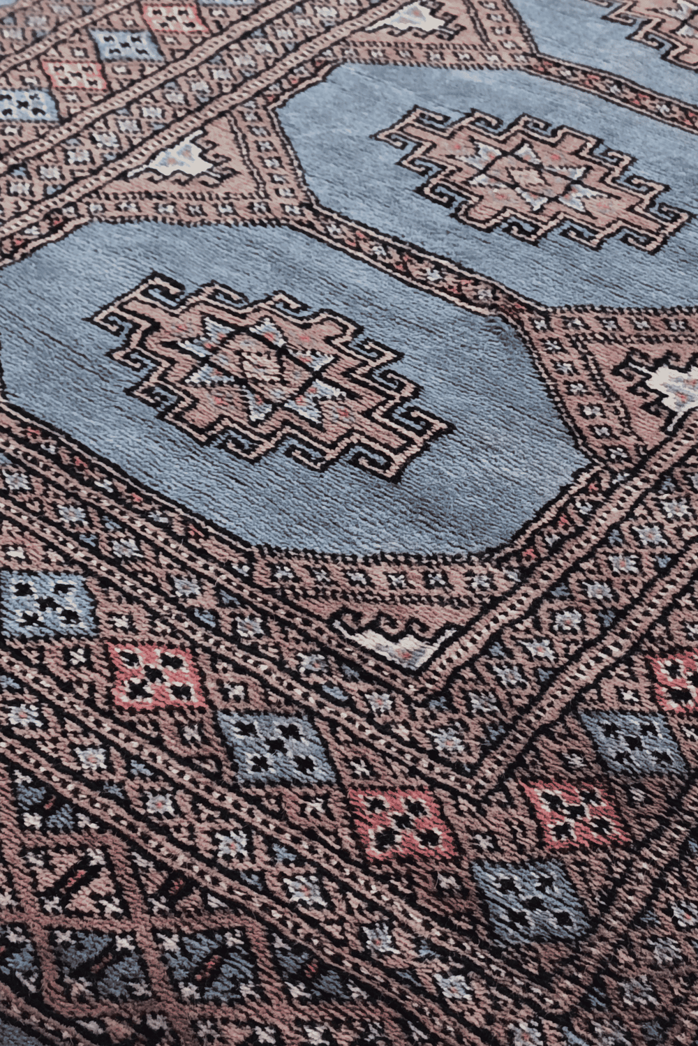 Stepped medallion detail in dusty blue and rose on Bokhara runner