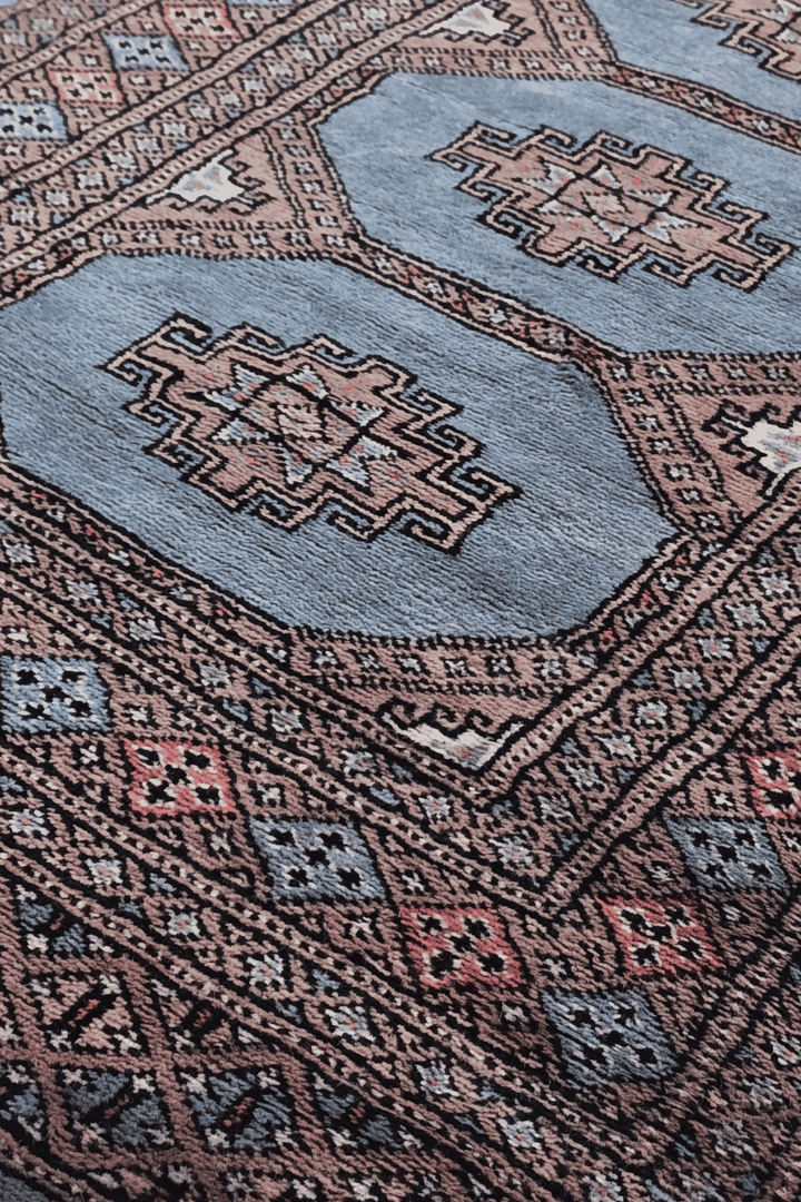 Stepped medallion detail in dusty blue and rose on Bokhara runner