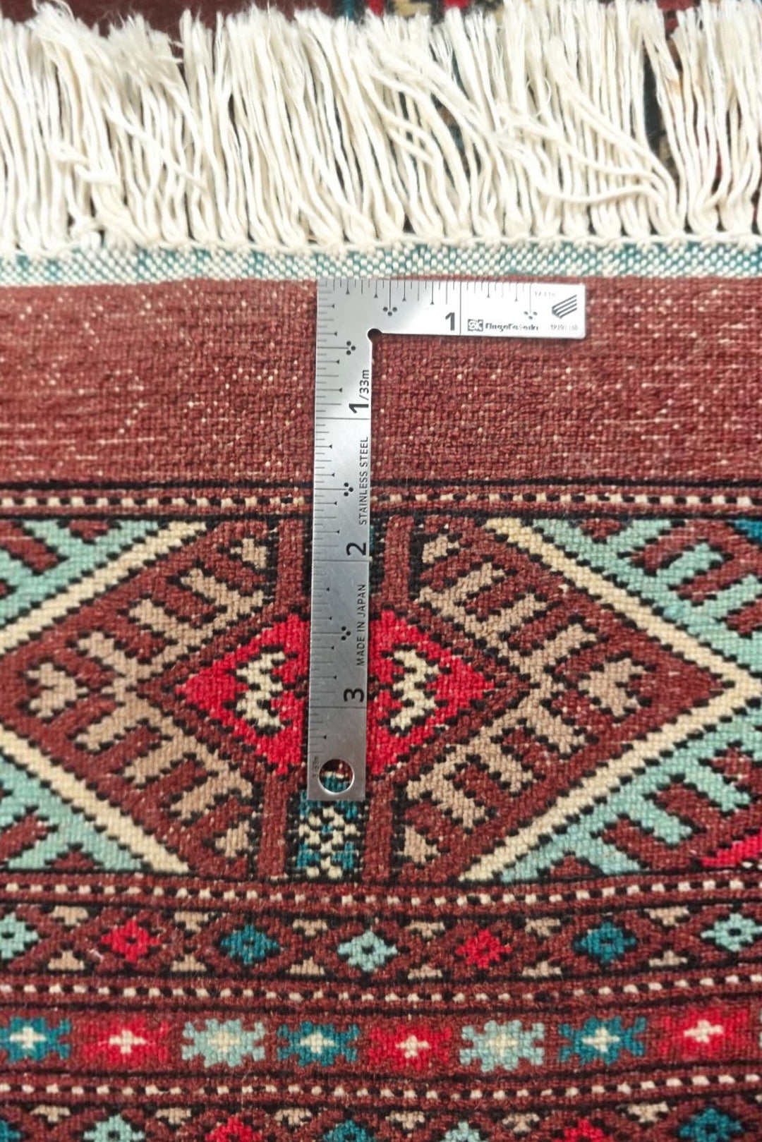 Corner of oxblood and blue Pakistani Bokhara hand-knotted rug
