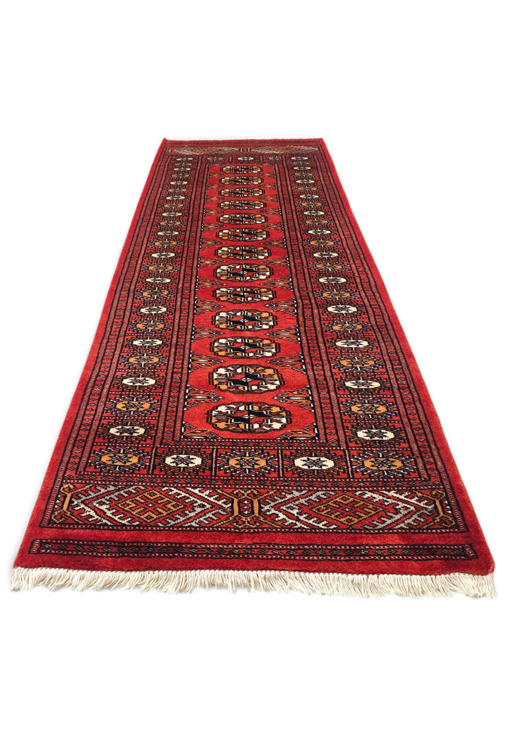 Border detail of red and orange hand-knotted Bokhara rug