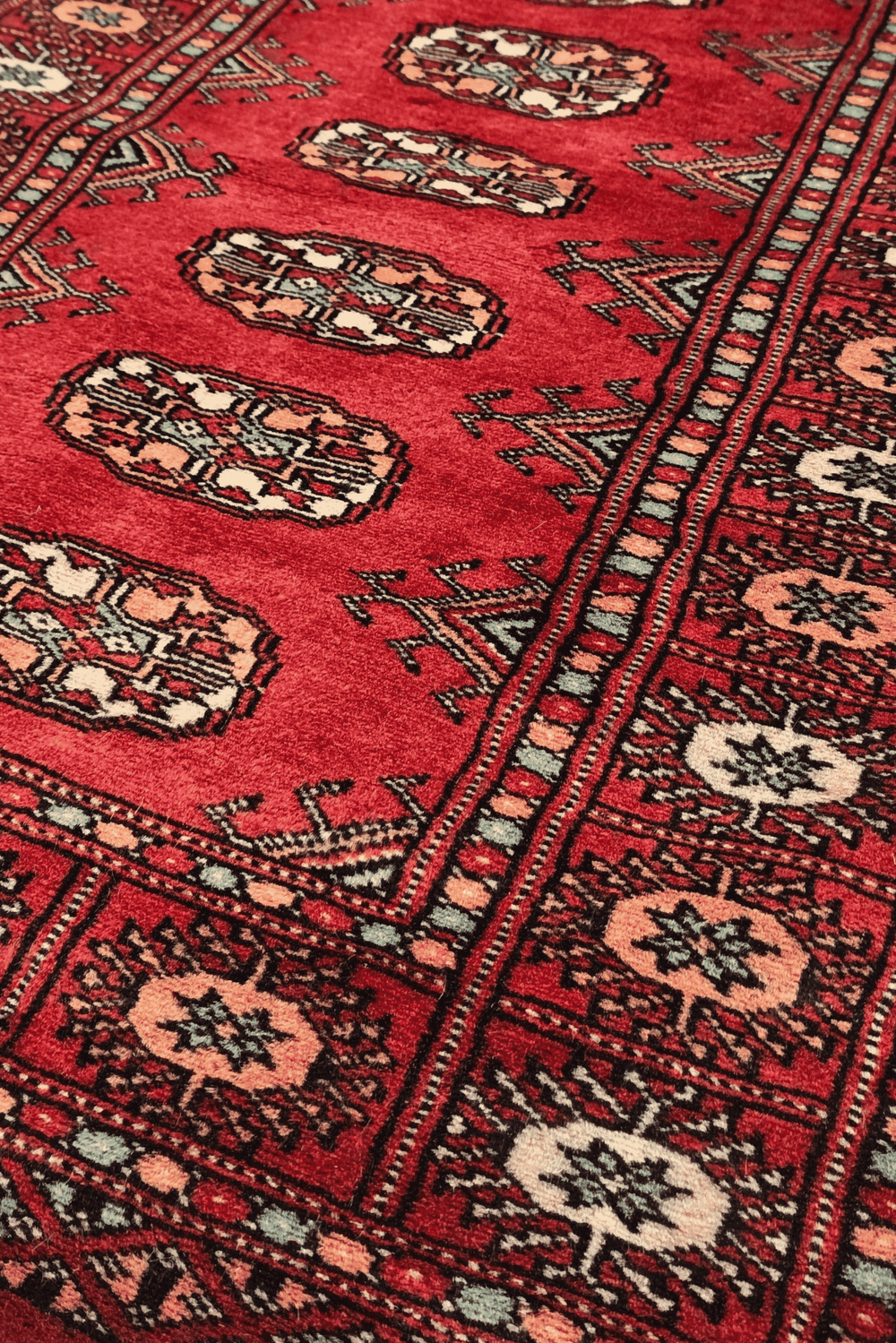 Turkmen gül motifs in ruby red and peach on small Bokhara rug