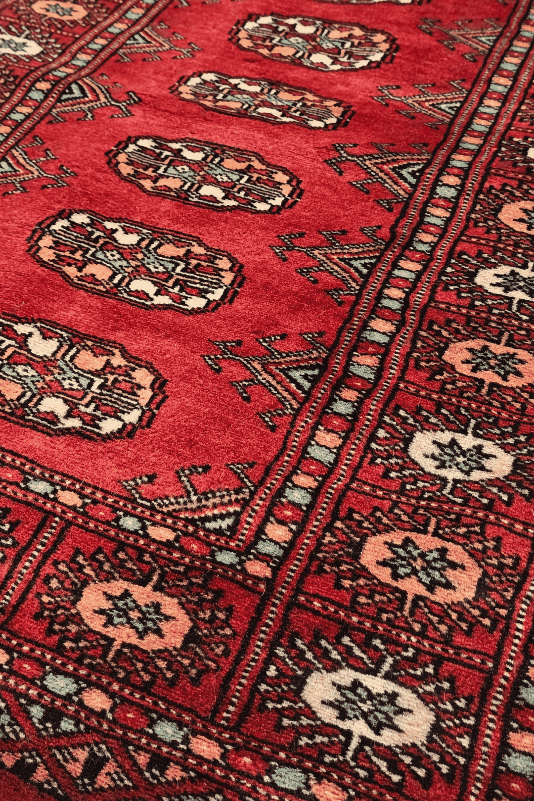 Turkmen gül motifs in ruby red and peach on small Bokhara rug