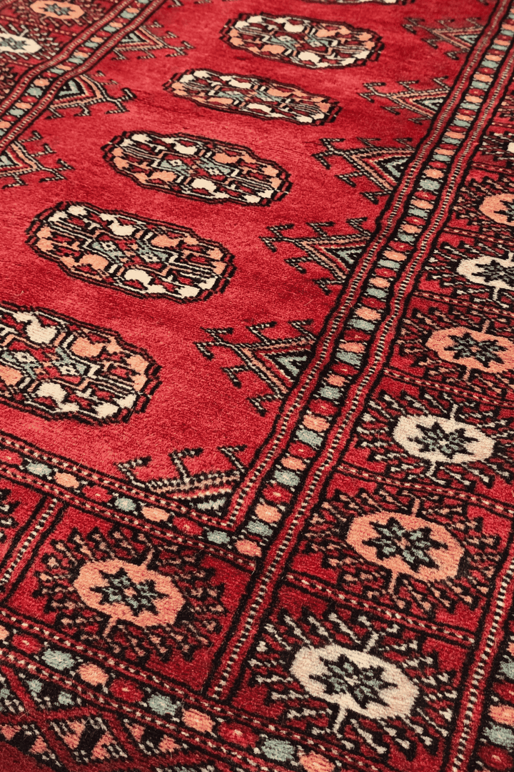 Turkmen gül motifs in ruby red and peach on small Bokhara rug