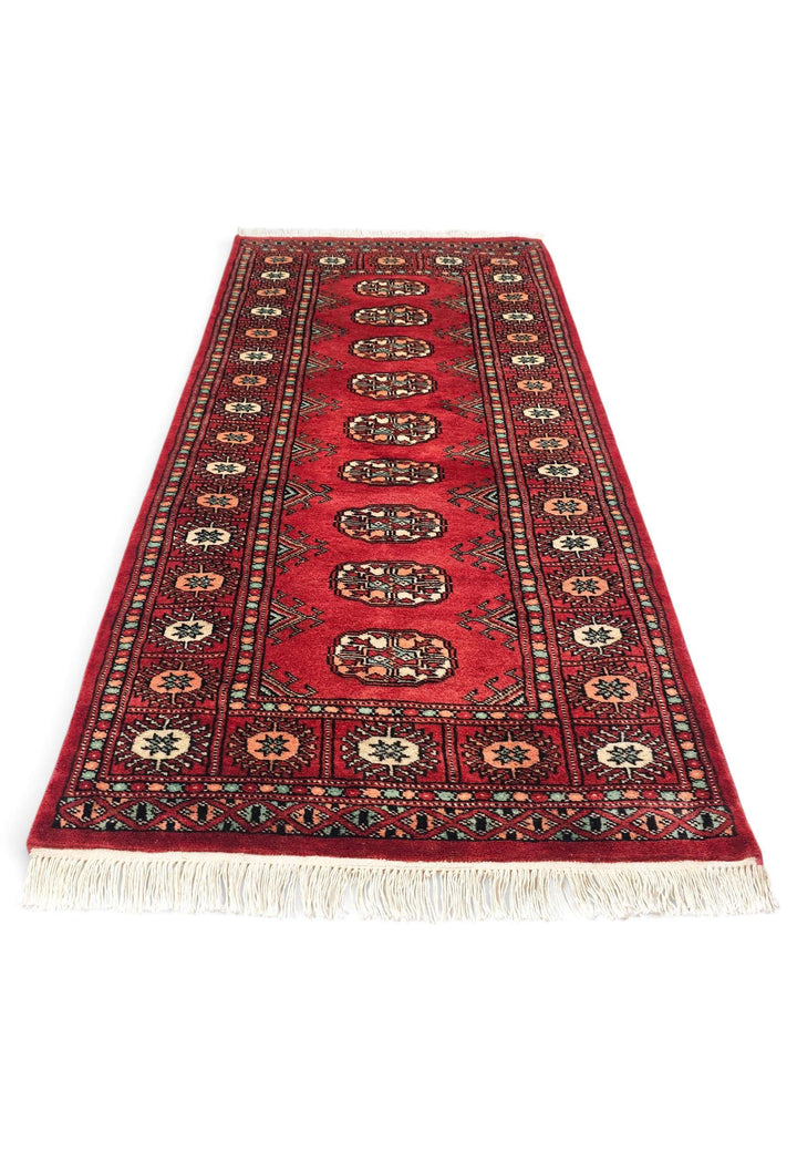 Border detail of ruby red and peach hand-knotted Bokhara rug
