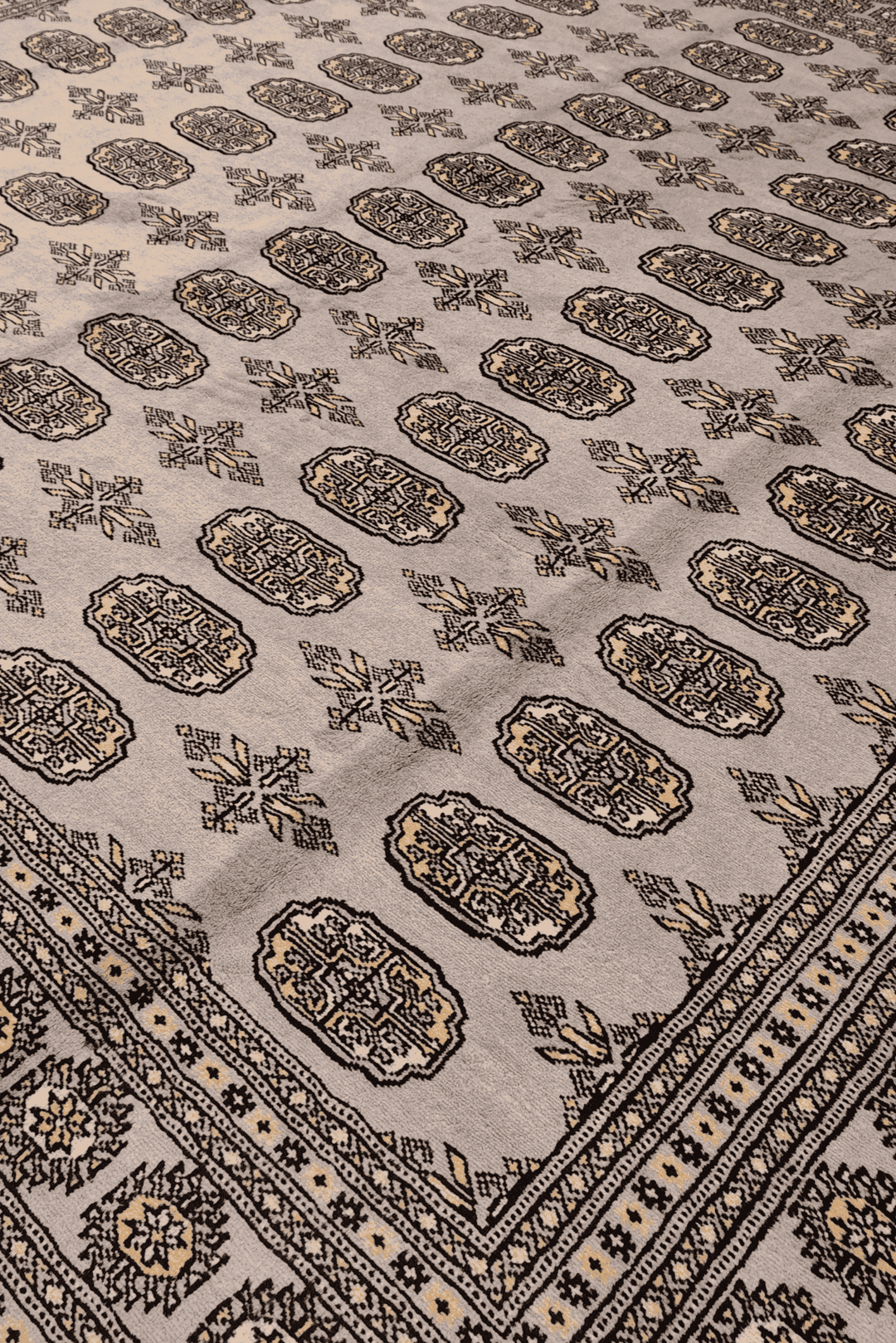 Border detail of warm grey hand-knotted square Bokhara rug