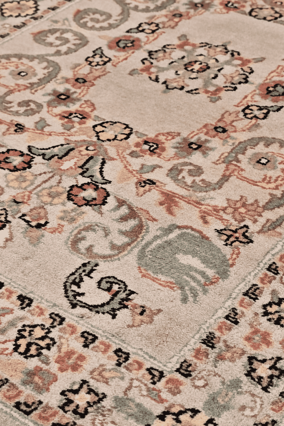 Scrolling leaf medallion detail in blush and sage on Pakistani rug