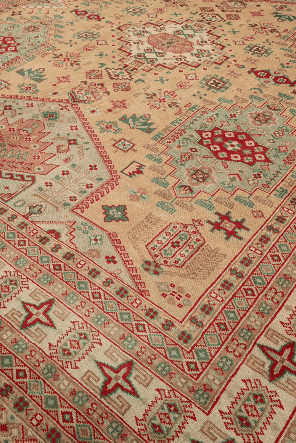 Caucasian medallion detail in camel and coral on Pakistani rug