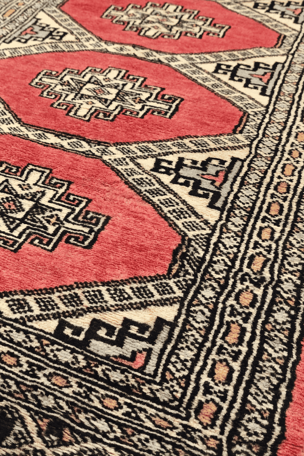 Stepped diamond gül motifs in coral and ivory on Jaldar rug