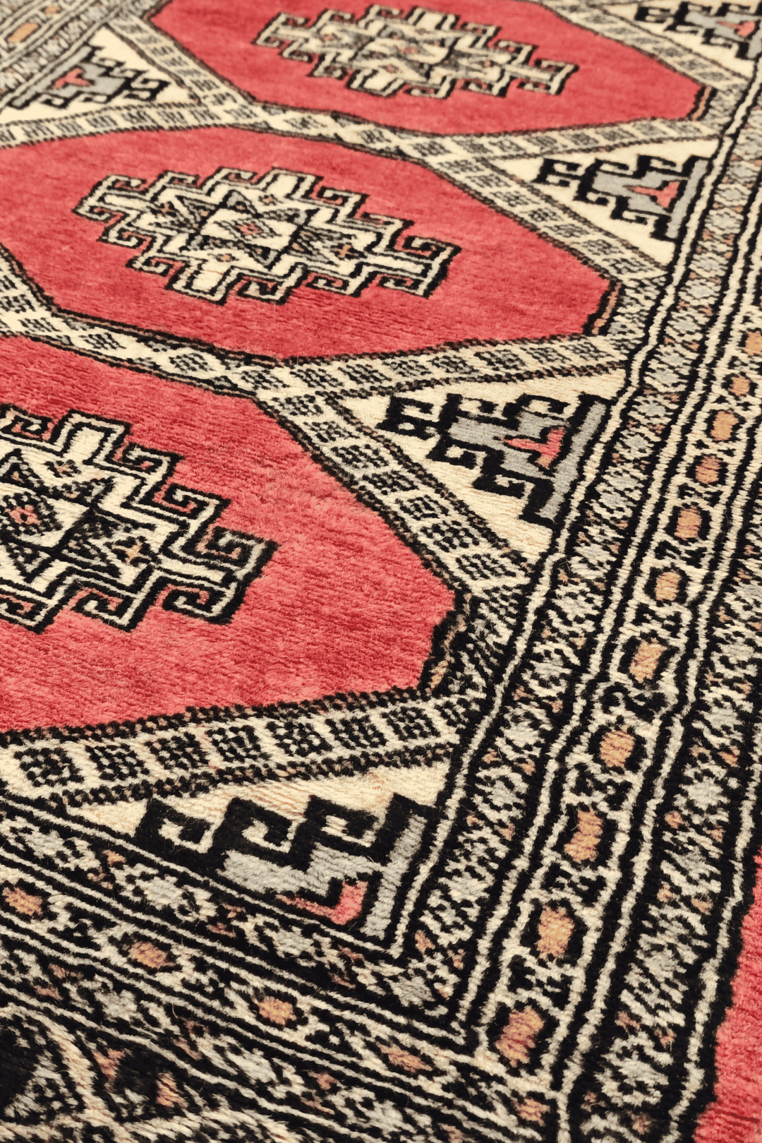 Stepped diamond gül motifs in coral and ivory on Jaldar rug
