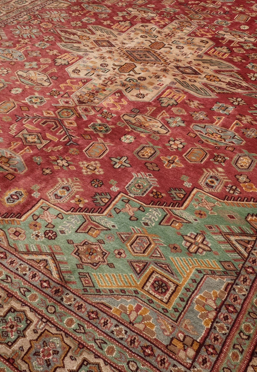 Tribal medallion detail in rust red and green on Jaldar rug