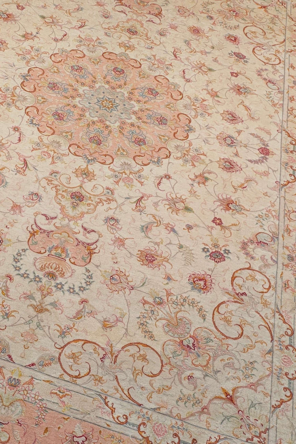 Scrolling leaf medallion detail in ivory and peach on Tabriz rug