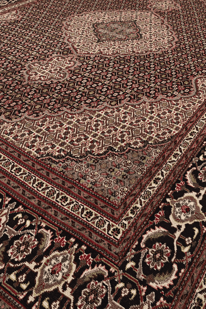 Border detail of burgundy mahi Tabriz hand-knotted rug