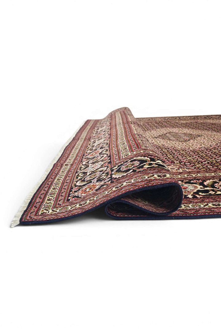 Corner of burgundy mahi Tabriz hand-knotted rug